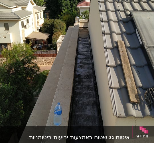 גג עם חומר איטום שחור ולוח עץ